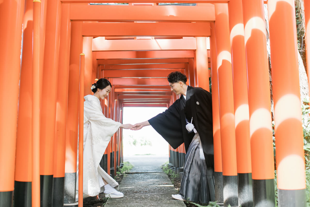 新発田の大友稲荷奥之院で朱色の鳥居を歩く白無垢の花嫁と紋付袴の花婿